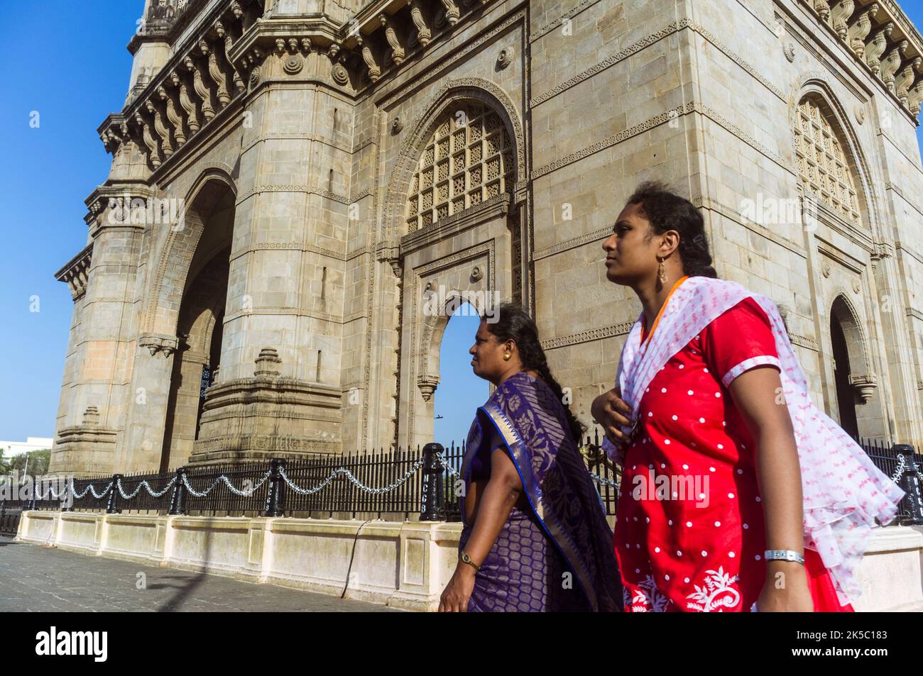Mumbai, Maharashtra, Indien : Indische Frauen gehen am Gateway of India monumentalen Bogen vorbei, der zwischen 1913 und 1924 im indo-sarazenischen Stil erbaut wurde. Stockfoto