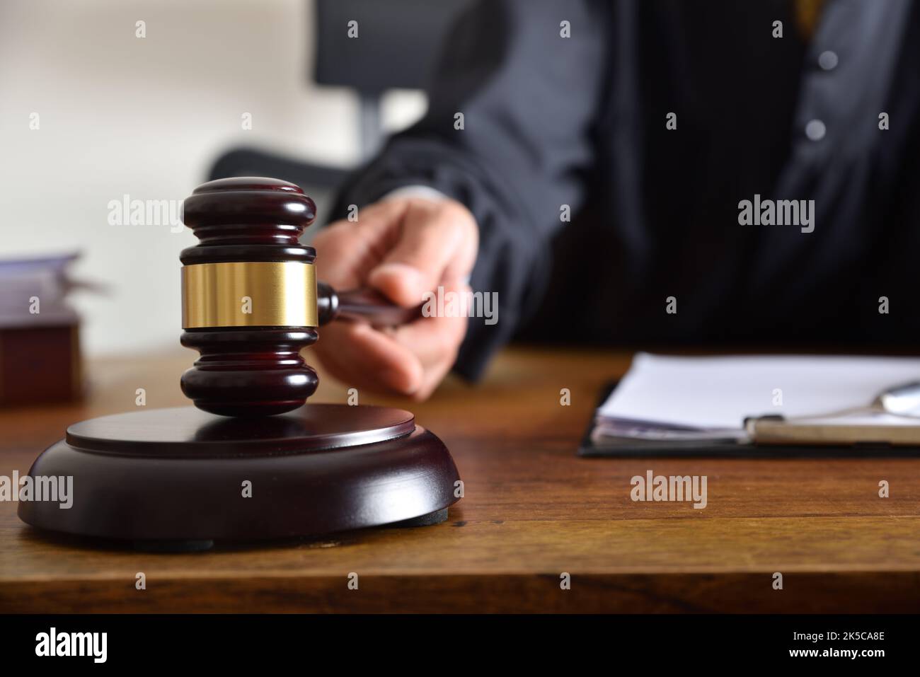 Detail eines Richters, der das Urteil gefällt, indem er mit dem Gavel auf einen Holztisch trifft. Vorderansicht Stockfoto