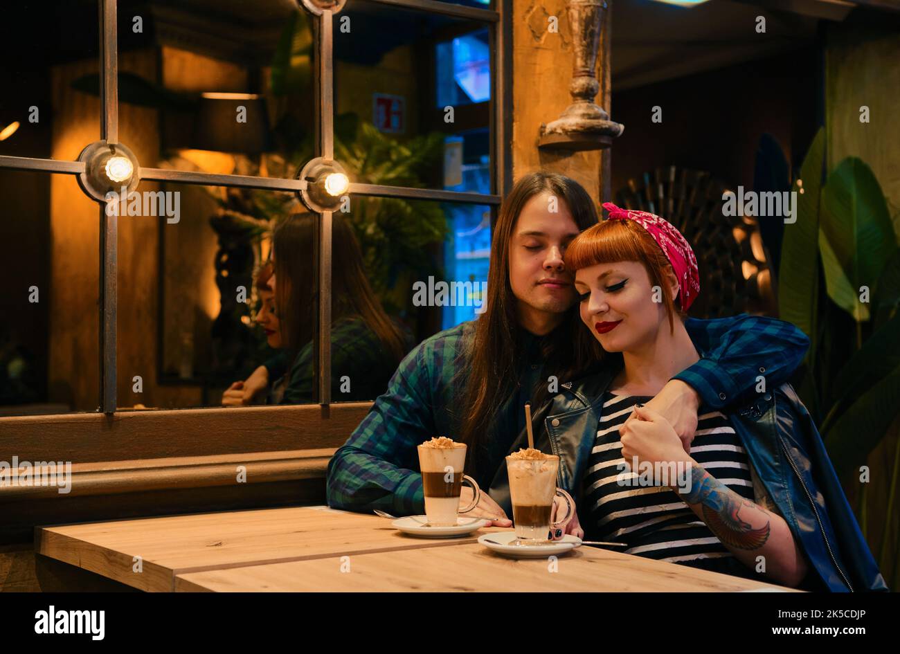Schönes Pin-up-Paar, das mit geschlossenen Augen in einem Café sitzt Stockfoto