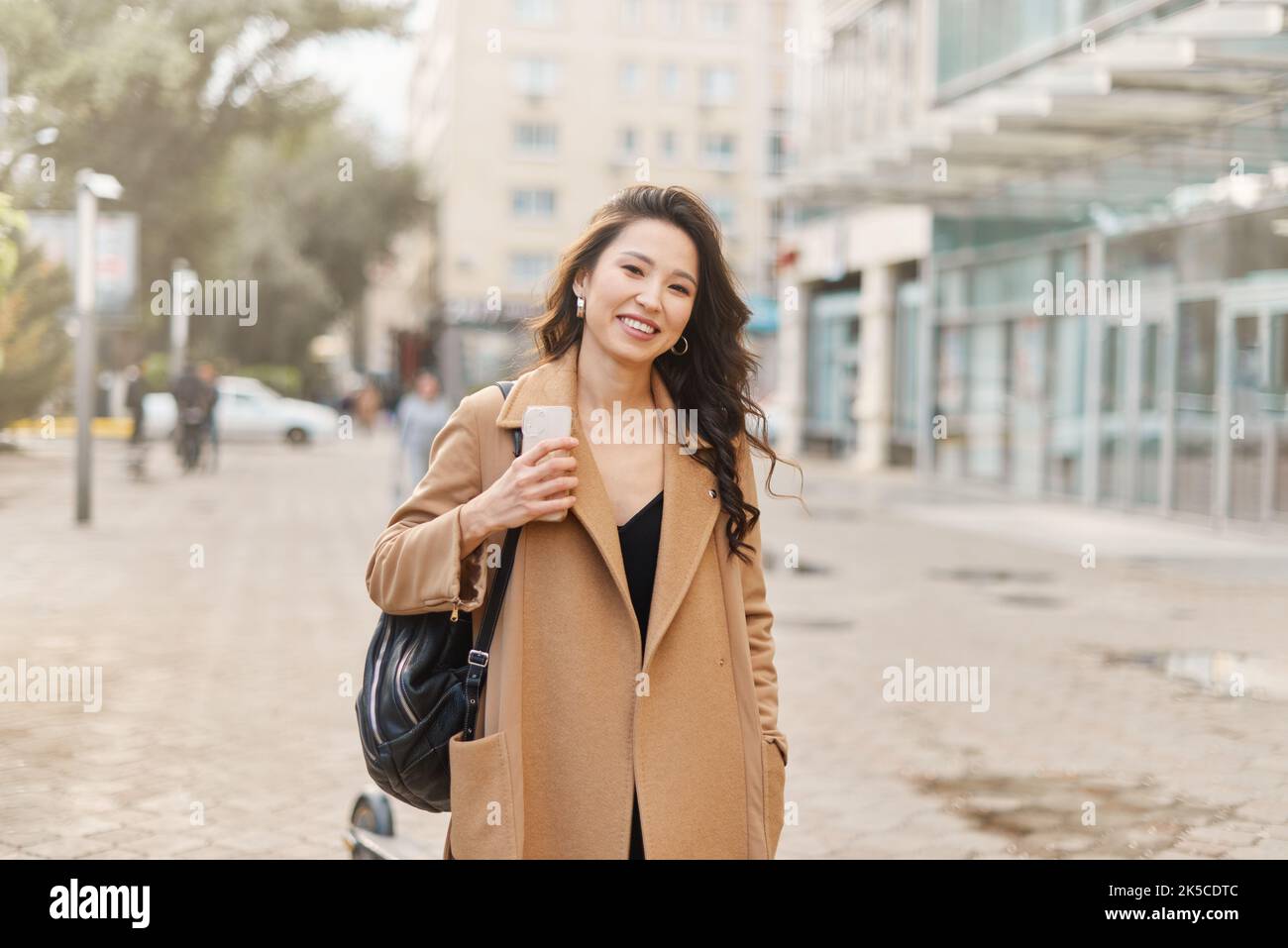 Lifestyle-Porträt hübsche asiatische kasachische Frau mit brillantem Lächeln auf der Straße Stockfoto