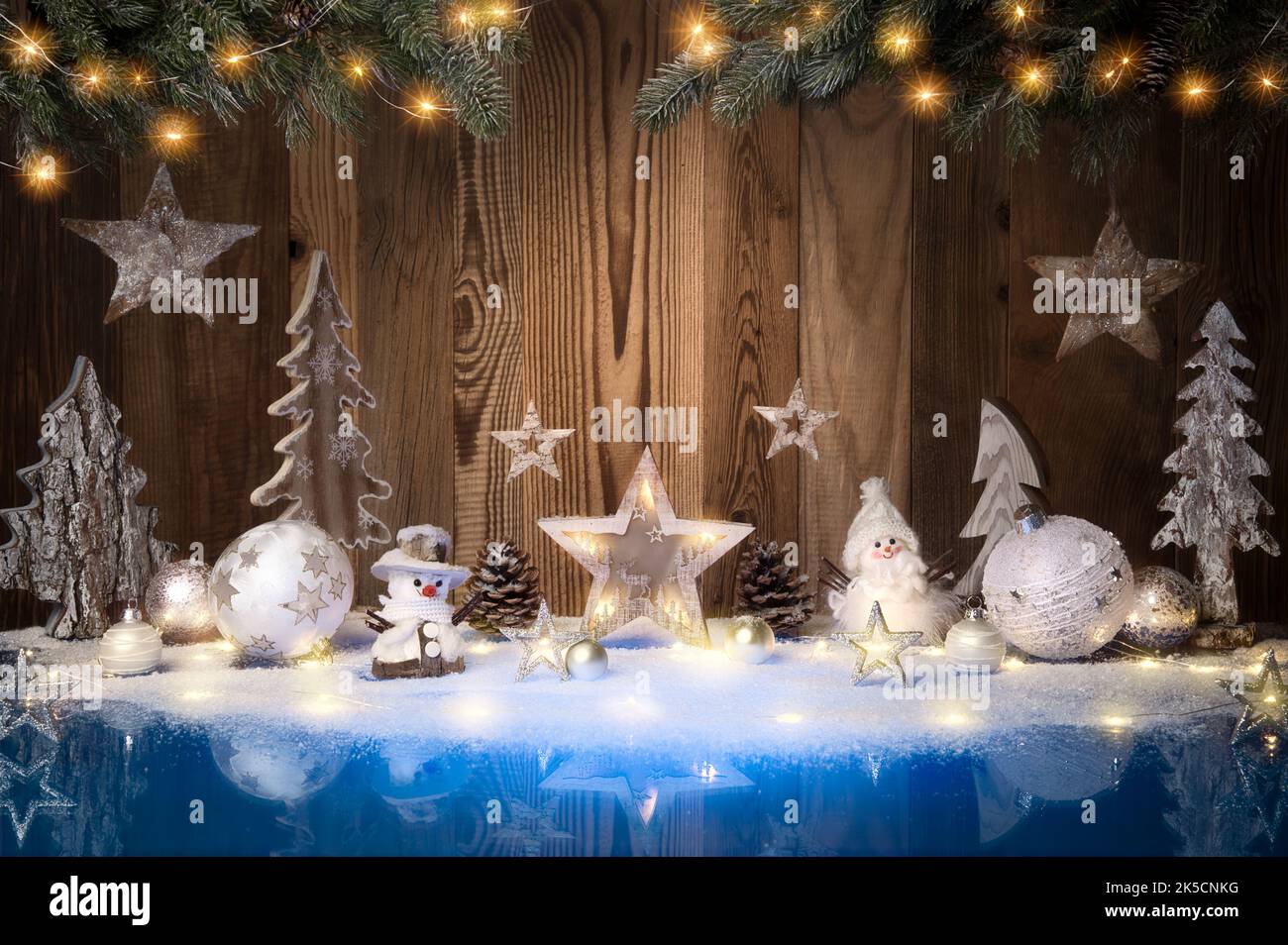 Weihnachtsschmuck, Lichter und Schnee auf blauer Oberfläche und Holzhintergrund mit Kopierraum Stockfoto