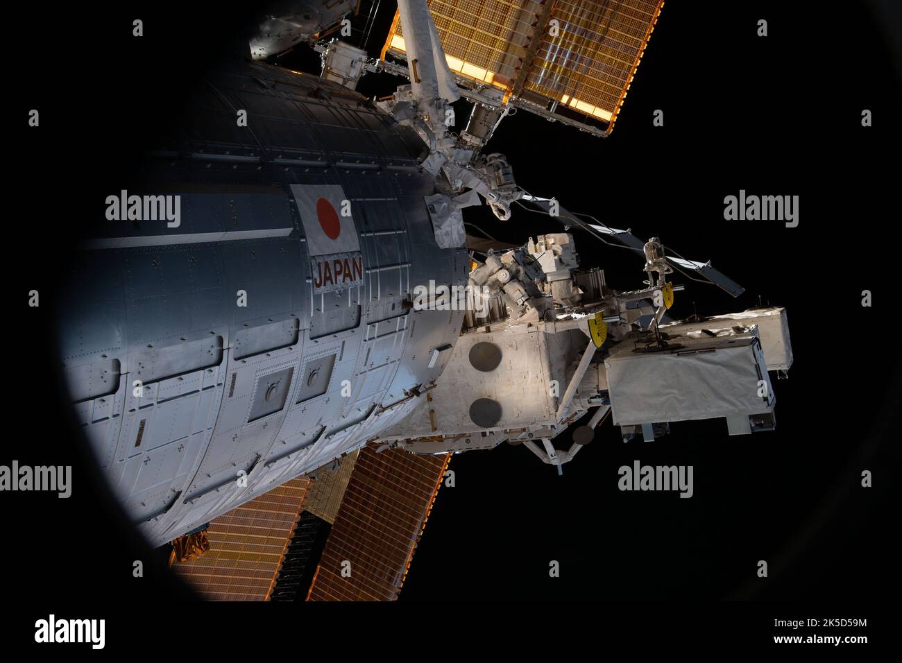 Durch das CST-100 Starliner-Fenster ist das Kibo-Labormodul von JAXA auf der ISS zusammen mit einem Teil seiner wichtigsten Solarzellen sichtbar. Stockfoto