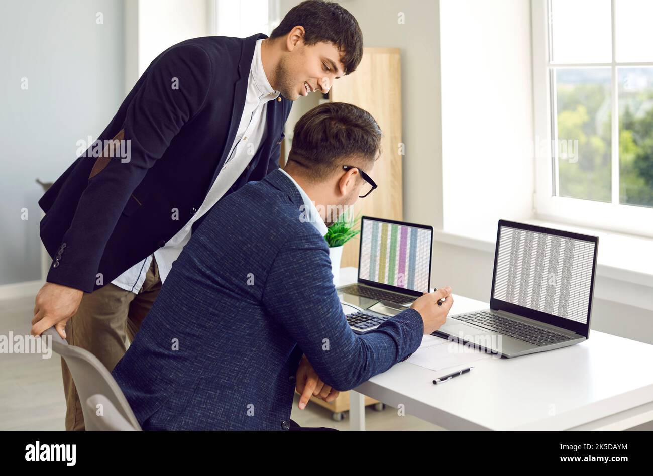 Lächelnde Geschäftsleute, die mit einem Laptop arbeiten, reden, kommunizieren, Startup planen, im Büro arbeiten. Zwei Geschäftskollegen in einem Meeting Stockfoto