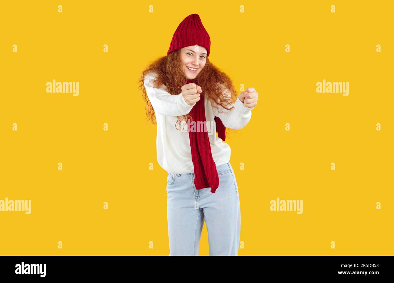 Teenager-Mädchen in warmen Hut und Schal tanzt mit freudigem Ausdruck und bewegt sich zum Rhythmus der Musik. Stockfoto