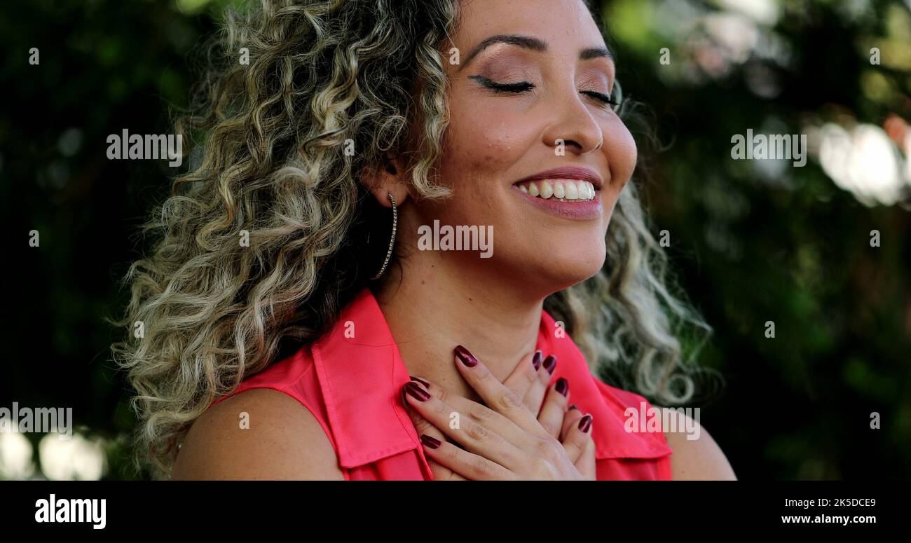 Latina Frau, die Hand auf die Brust legt lächelnd einen tiefen Atemzug nimmt, fühlt DANKBARKEIT Stockfoto