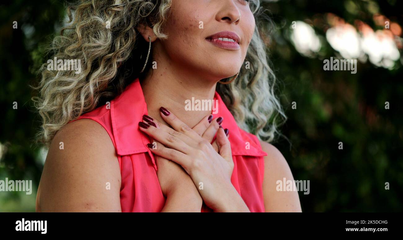 Latina Frau, die Hand auf die Brust legt lächelnd einen tiefen Atemzug nimmt, fühlt DANKBARKEIT Stockfoto