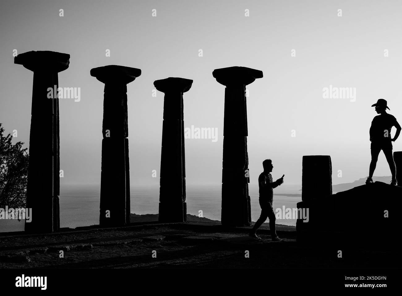 Canakkale, Türkei - 4 2021. August: Tempel der Athene in Assos mit Silhouette von Frau und Mann. Schwarzweiß-Foto. Stockfoto