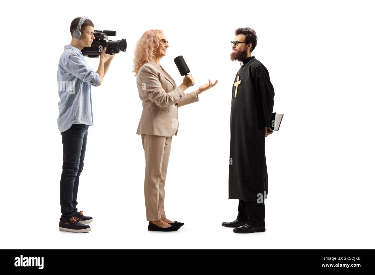 Eine Reporterin interviewte einen katholischen Priester und einen Kameramann, der isoliert auf weißem Hintergrund Aufnahmen Stockfoto