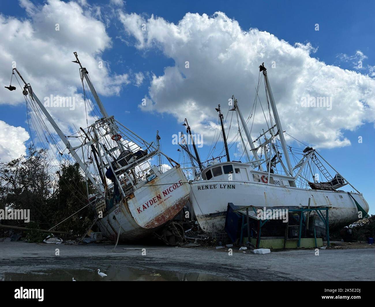 Fotos zeigen beschädigte Garnelenboote und Trümmer nach dem Unwehen des Unwhrens Ian in Fort Myers. Hurrikan Ian verließ diesen Yachthafen von Fort Myers zerstört, mit Booten herumgeschleudert und Piers in der Nähe einer Brücke zum Fort Myers Beach pulverisiert. Stockfoto