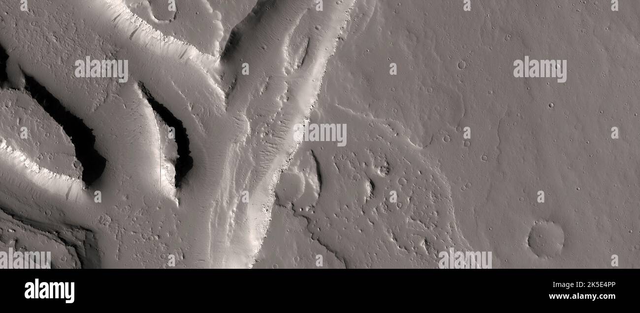 Marsatlandschaft. Dieses HiRISE-Bild zeigt Landformen auf der Marsoberfläche, Kanäle und Lavaströme auf dem Tharsis-Plateau, östlich des Olympus Mons. Die einfachste Hypothese ist, dass die Lava die Kanäle geschnitzt hat, aber es ist nicht leicht zu verstehen, wie Lava tief in das Grundgestein erodieren kann. Die allgemein favorisierte Hypothese ist, dass Wasser die Kanäle geschnitzt hat, und später folgten Ausbrüche von Lava den bereits geschnitzten Kanälen, oder vielleicht wurden Lava und Wasserflüsse mit der Zeit verschachtelt. Das Bild zeigt Gelände mit einer Länge von weniger als 5 km (3 mi). Eine einzigartige optimierte Version von NASA-Bildern. Quelle: NASA/JPL/UArizona Stockfoto