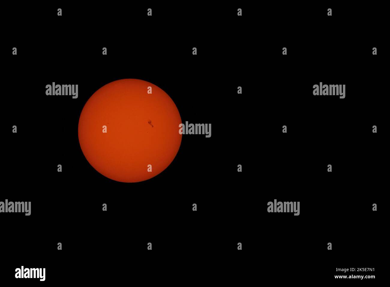 Sonnenflecken an einer orangefarbenen Sonne. Einer ist groß, der Rest ist kleiner. Turbulenzen sind auf der Sonnenoberfläche sichtbar, das ist kein Lärm. Stockfoto