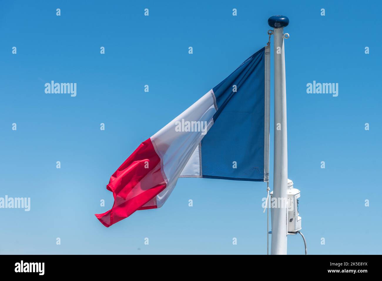 Französische Flagge auf der Stange über einem blauen Himmel. Stockfoto