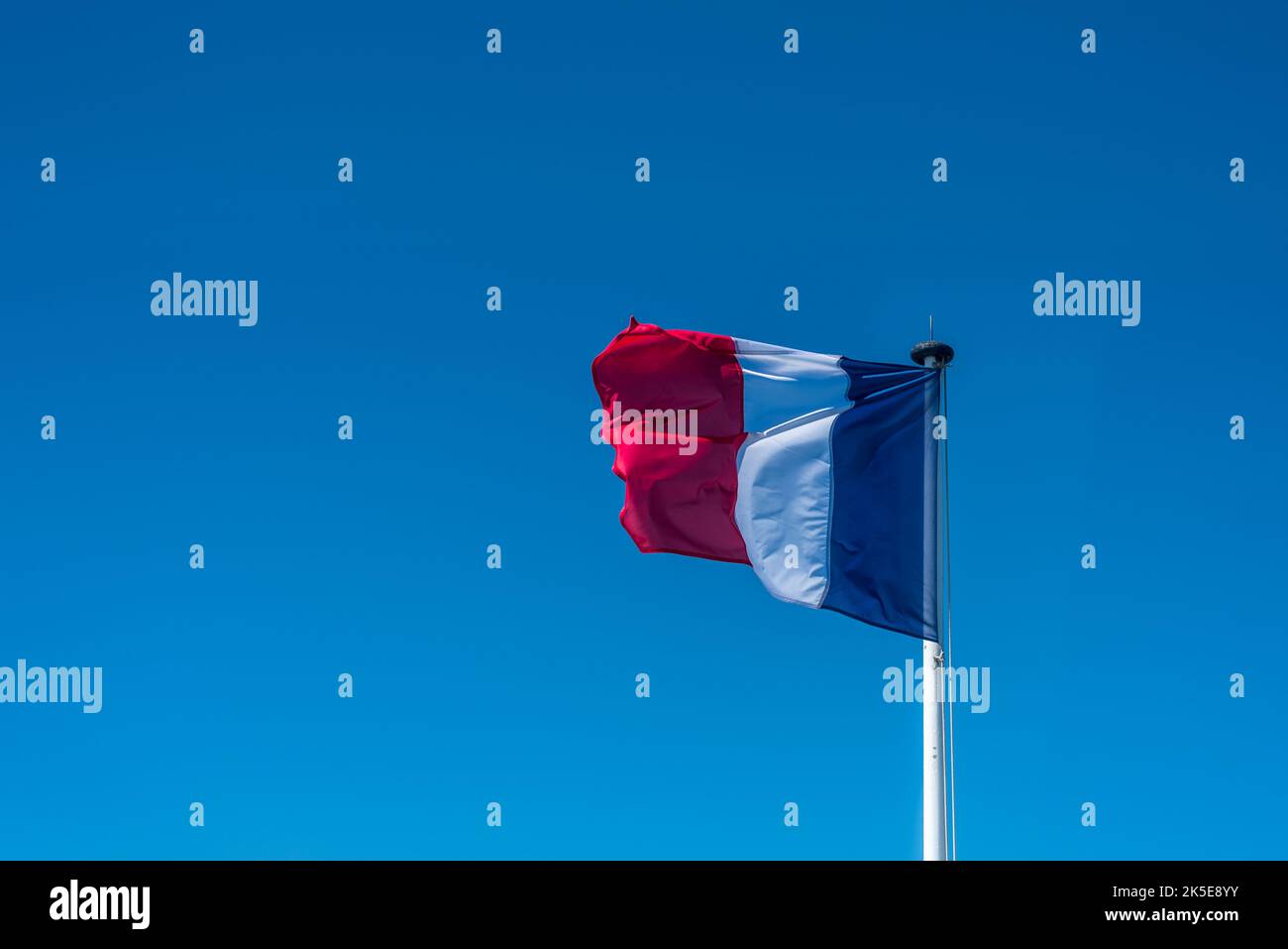 Französische Flagge auf der Stange über einem blauen Himmel. Stockfoto
