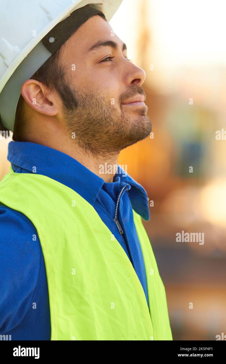 Überwachung der Bauarbeiten. Ein gutaussehender Ingenieur, der nachdenklich davonschaut. Stockfoto
