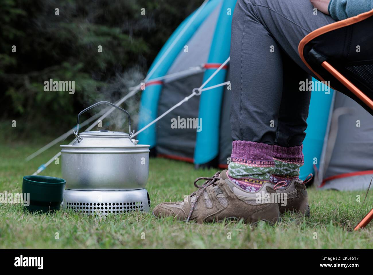 Frau kocht einen Wasserkocher auf einem Campingkocher. Stockfoto