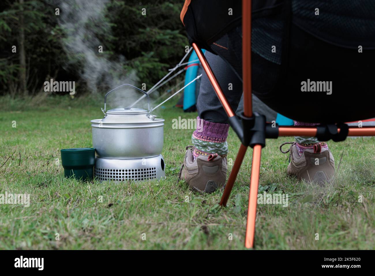 Frau kocht einen Wasserkocher auf einem Campingkocher. Stockfoto