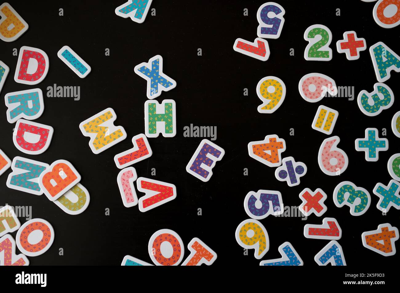 Draufsicht auf Zahlen und Buchstaben vor schwarzem Hintergrund Stockfoto