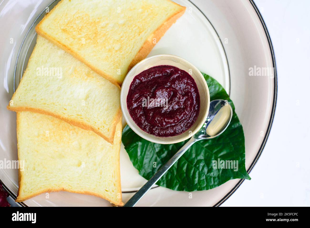 Hibiskusmarmelade und Toasts gegen das Glas mit Marmelade und Hibiskusblüten Stockfoto