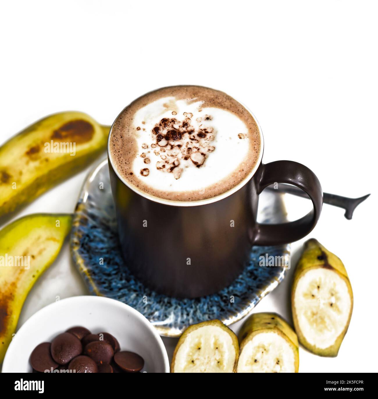 Bananenschokolade-Latte mit frischen Bananen- und Schokoladentropfen auf weißem Tisch Stockfoto