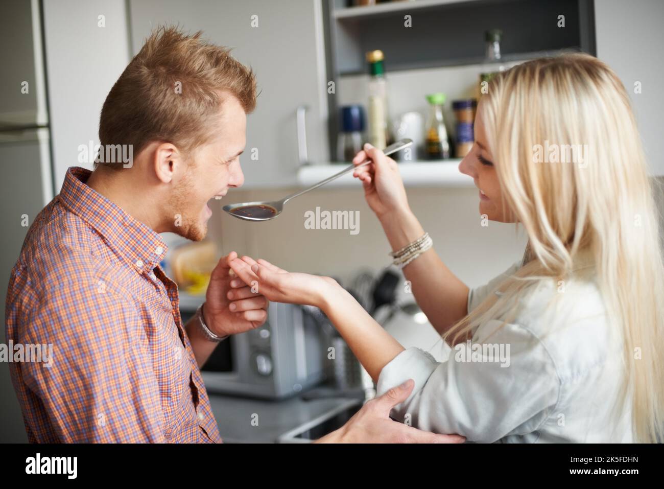 Sagen Sie mir, wie es schmeckt. Eine junge Frau, die ihrem Freund etwas zu essen gibt. Stockfoto