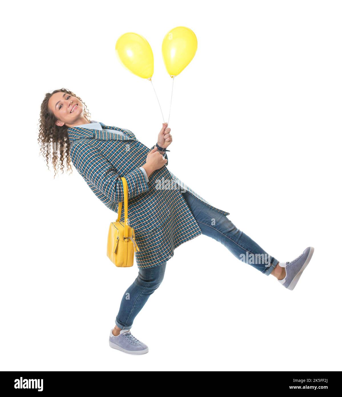 Schöne junge Mädchen in einem leichten Mantel mit einer gelben Tasche Spaziergänge mit gelben Ballons Stockfoto