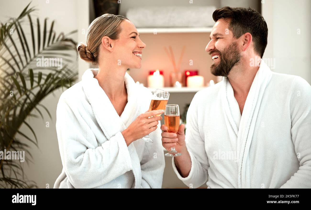 Champagner, Toast und ein Paar feiern in einem Spa für Liebe, Hochzeit oder Geburtstag zusammen. Glücklich, entspannt und ruhig jubeln Mann und Frau mit einem Glas Stockfoto