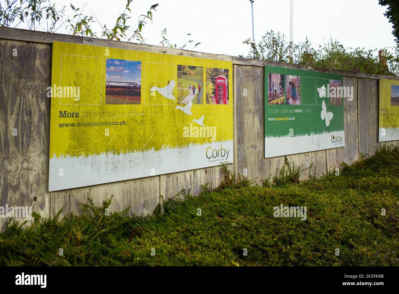 Verzweifelte und verzweifelte Plakate vor dem Bahnhof Corby, die für die Kampagne „mehr in Corby“ werben Stockfoto