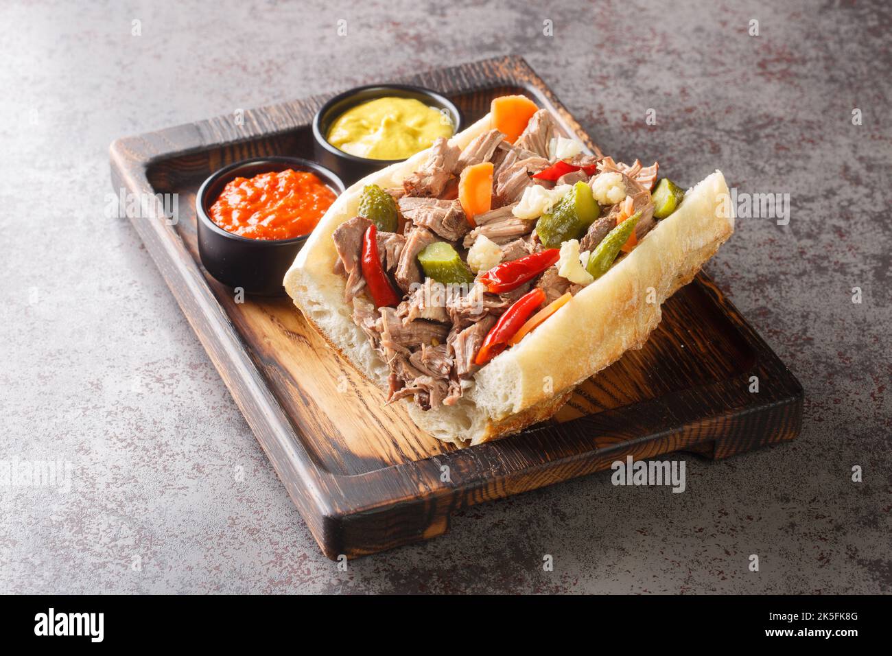 Köstliches italienisches Rindfleisch-Sandwich in Chicago mit langsam gekochtem Rindfleisch und Giardanarra-Nahaufnahme auf einem Holztablett auf dem Tisch. Horizontal Stockfoto