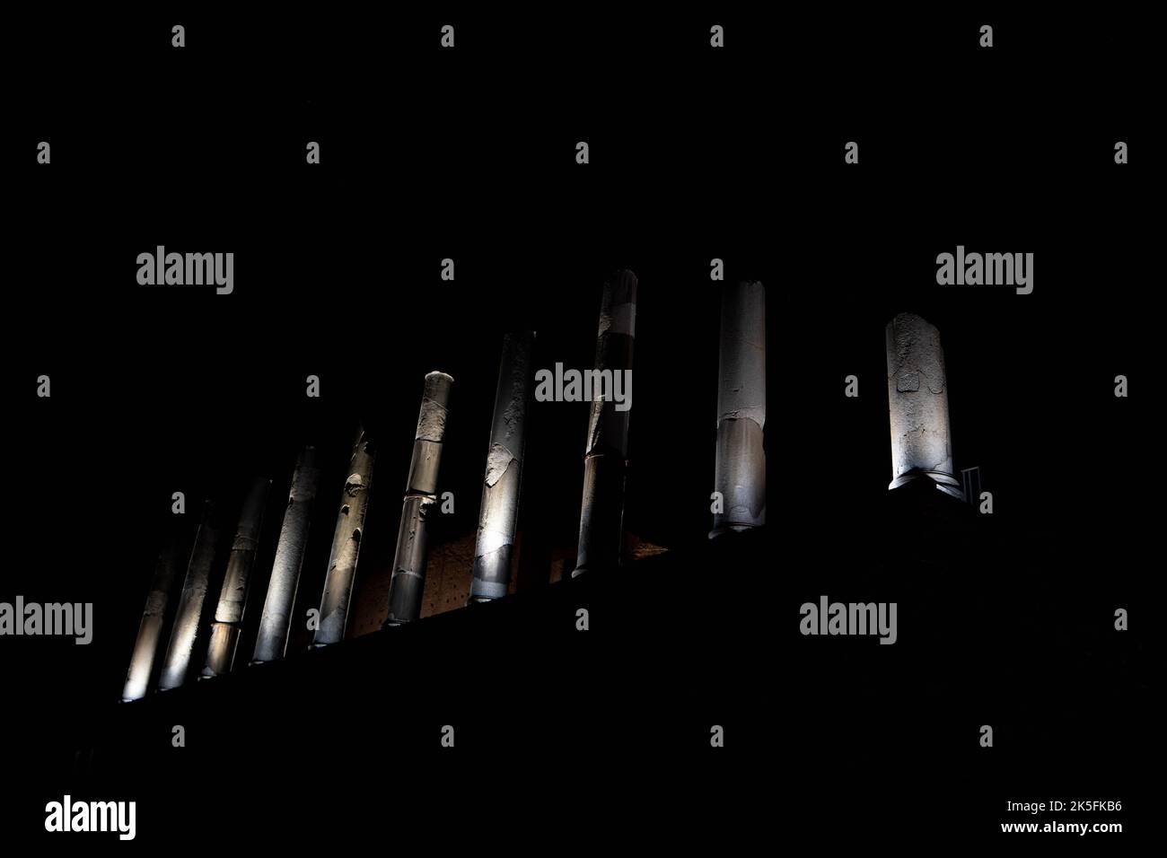 Dramatische nächtliche Beleuchtung der antiken römischen Säulen vor dunklem Himmel Stockfoto