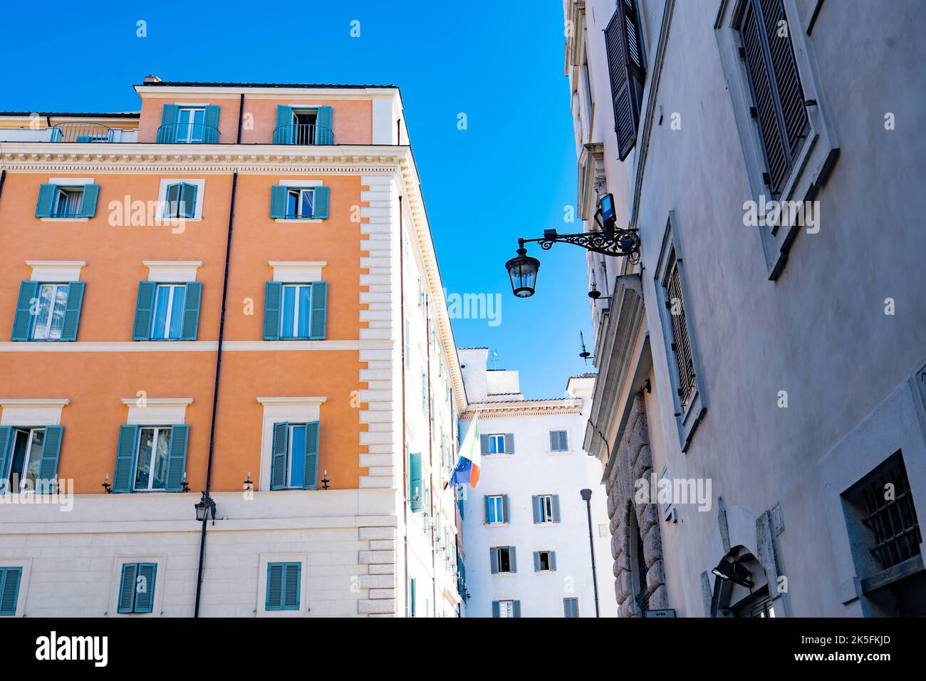 Farbenfrohe italienische Architektur mit türkisfarbenen Fensterläden vor strahlend blauem Himmel in Rom Stockfoto
