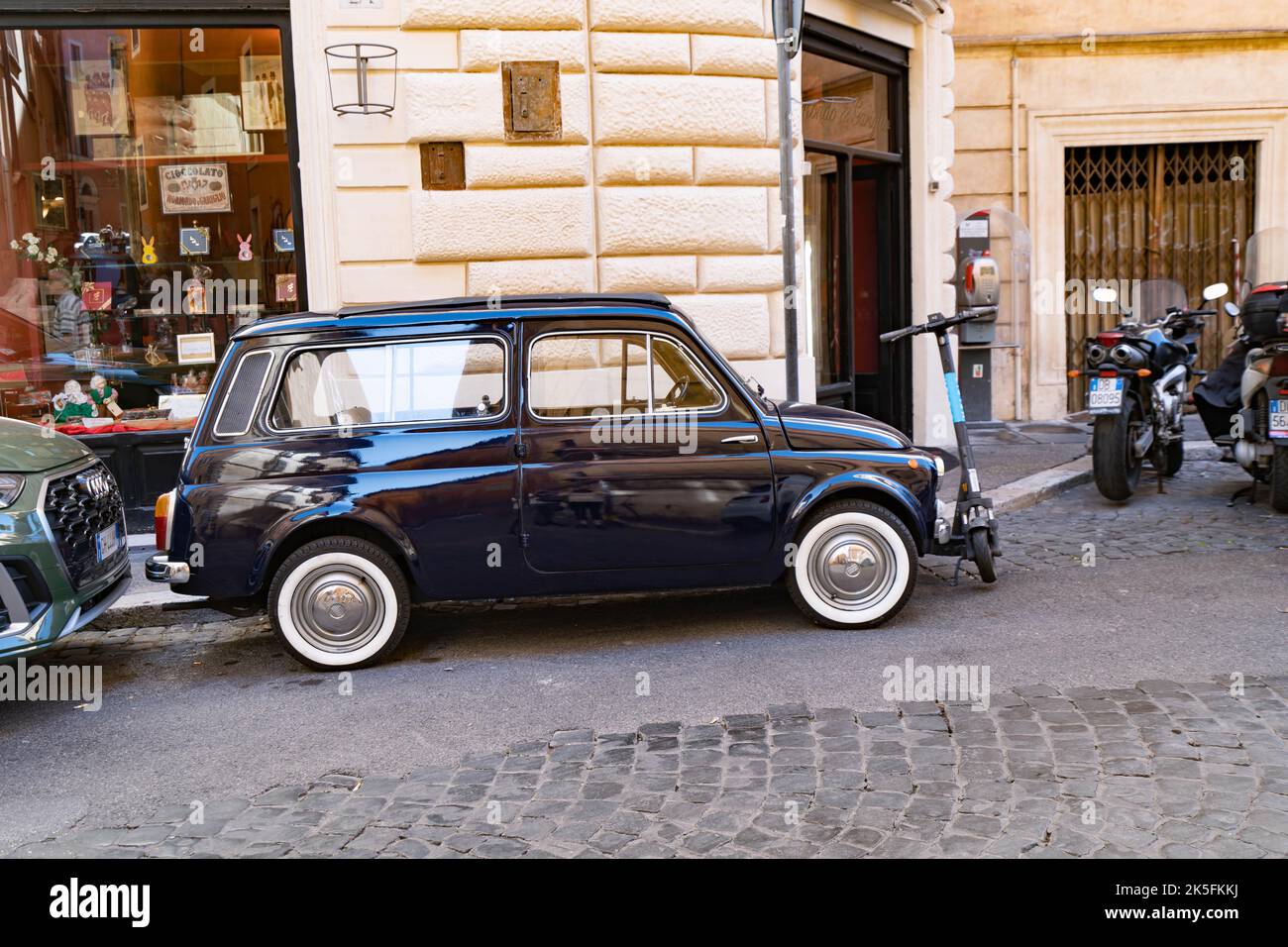 Klassisches dunkelblaues Fiat 500, das auf der Kopfsteinpflasterstraße in Rom geparkt ist Stockfoto