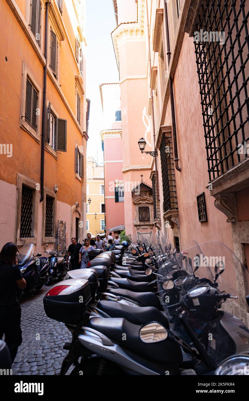 Enge römische Straße mit geparkten Motorrollern zwischen farbenfrohen historischen Gebäuden Stockfoto