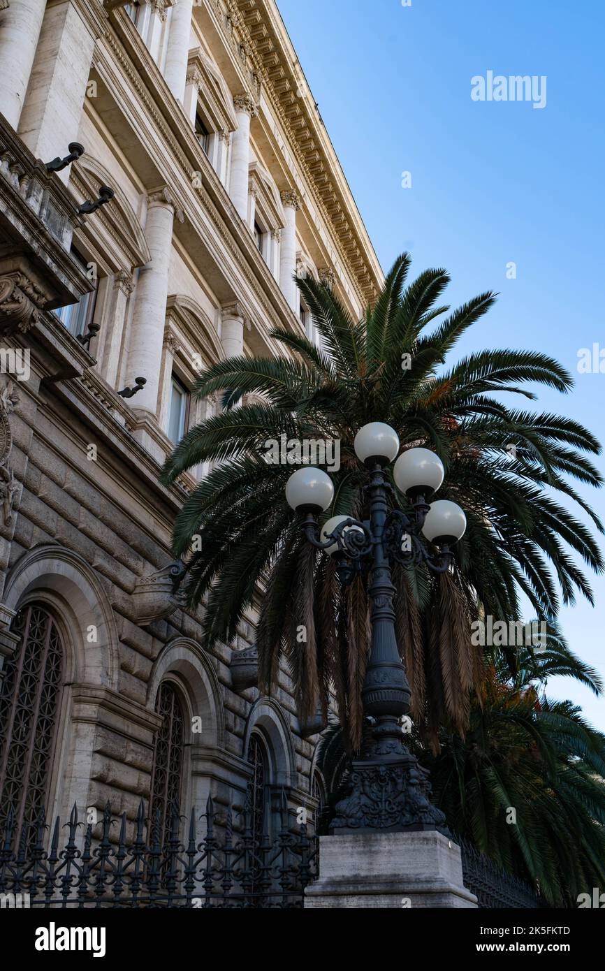 Kunstvolle Straßenlaterne mit Palme vor der Fassade klassischer römischer Architektur Stockfoto