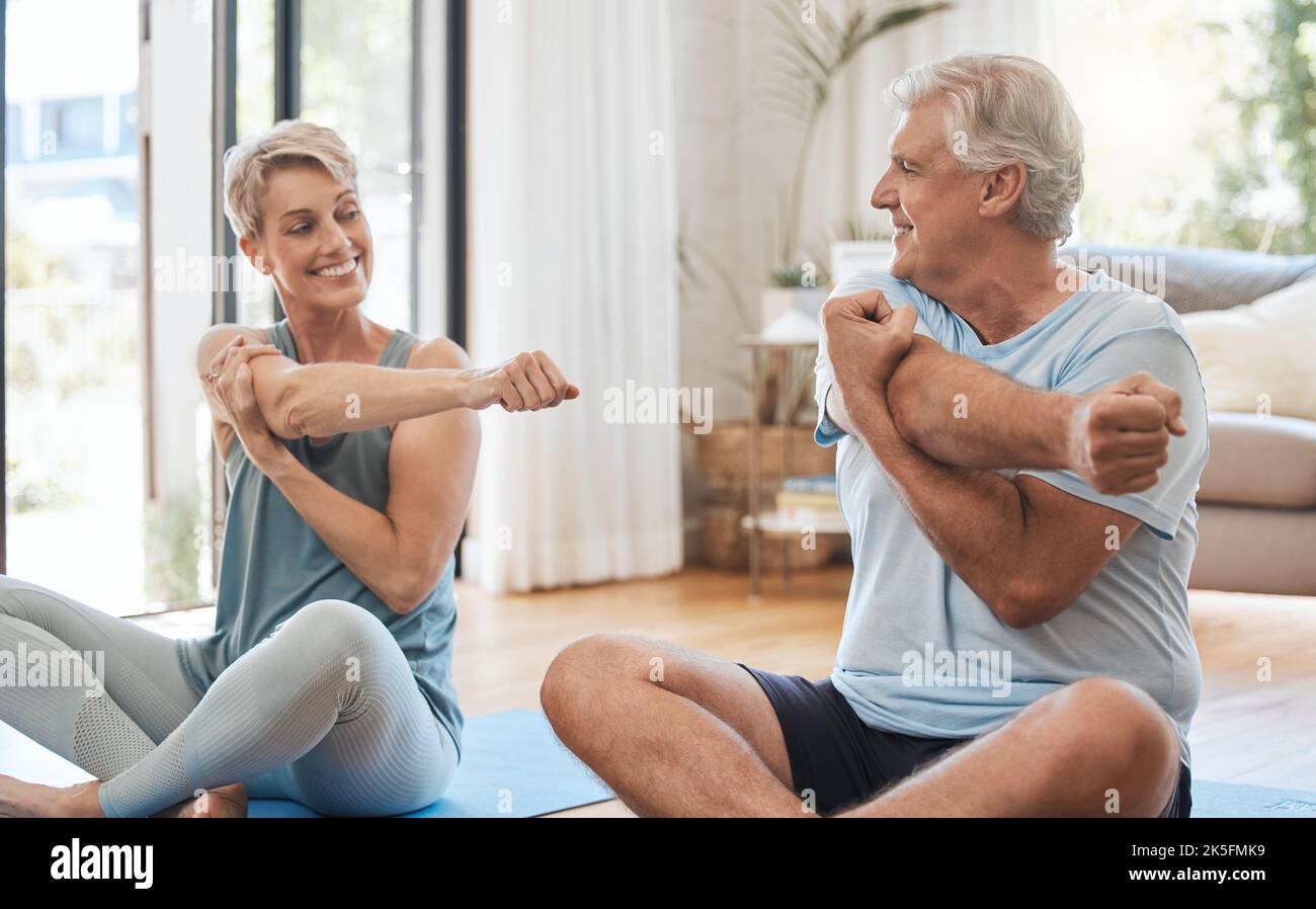 Stretching, Heimfitness und Seniorenpaar trainieren gemeinsam auf dem Wohnzimmerboden im Haus. Glücklicher älterer Mann und Frau, die Yoga machen, Pilates Stockfoto