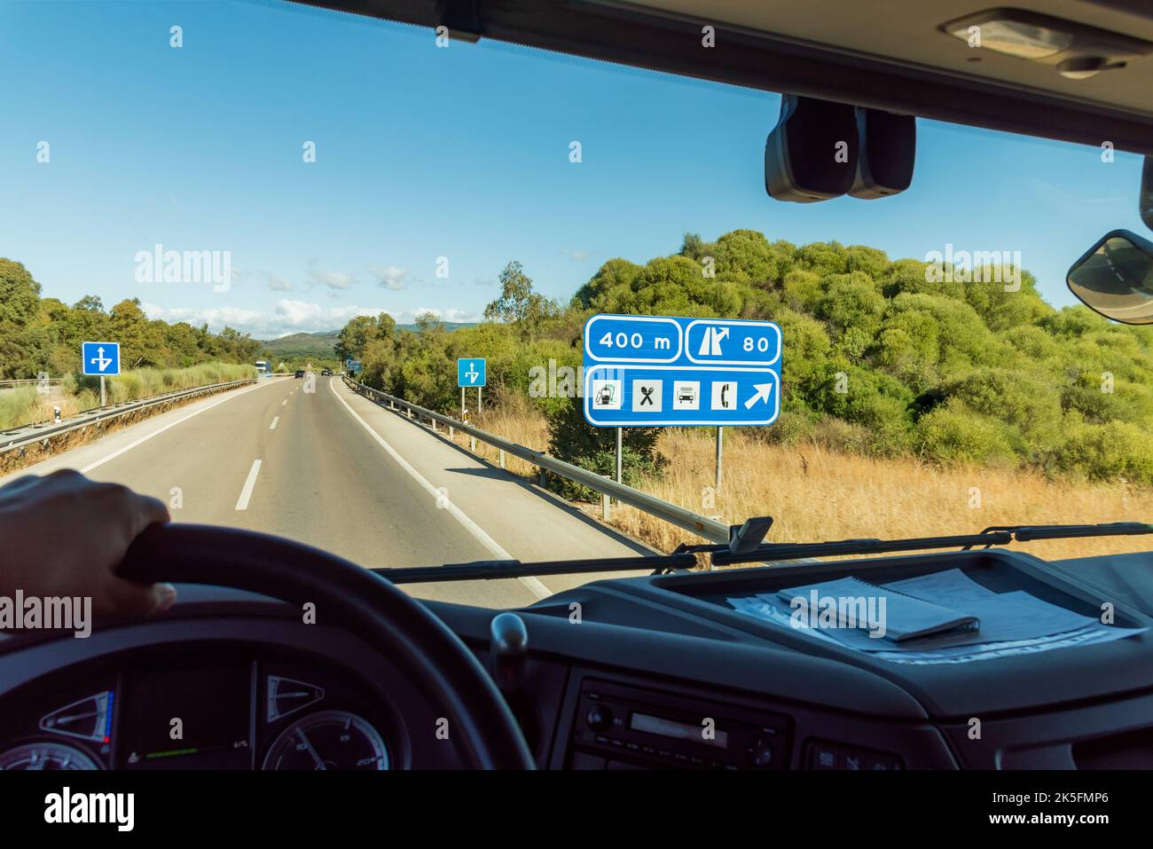 Blick vom Fahrersitz auf einen Lkw mit einem Schild, das auf einen nahe gelegenen Servicebereich hinweist. Stockfoto