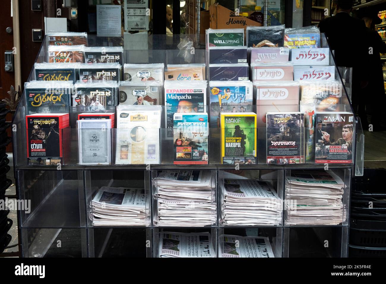 Zeitungskiosk mit Zeitungen und Zeitschriften, hauptsächlich in Jiddisch. Auf der Lee Avenue in Williamsburg, Brooklyn, New York City. Stockfoto