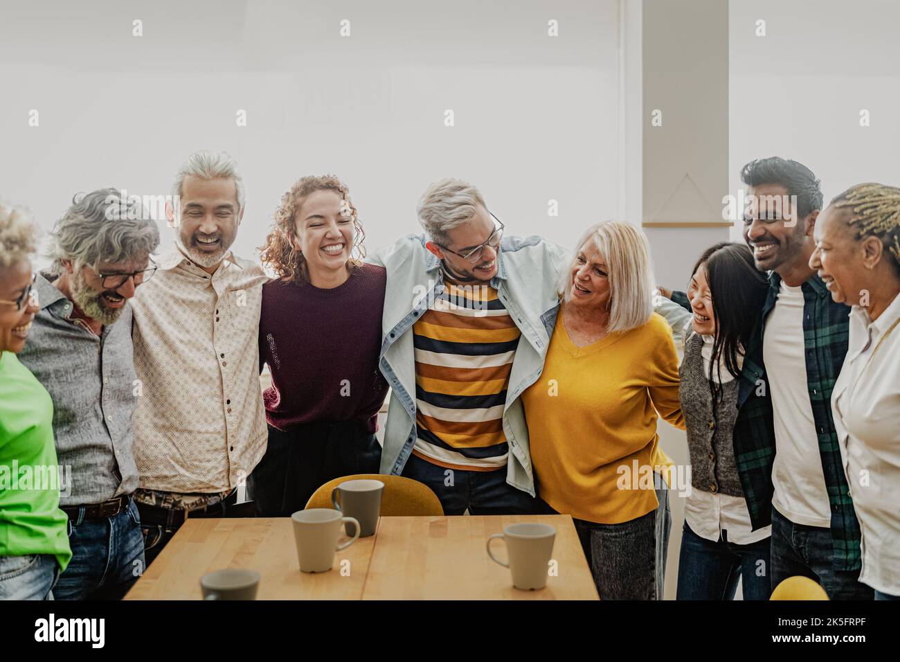 Fröhliche, multirassische Menschen mit unterschiedlichen Alters und Ethnien, die zu Hause eine Tasse Kaffee trinken Stockfoto