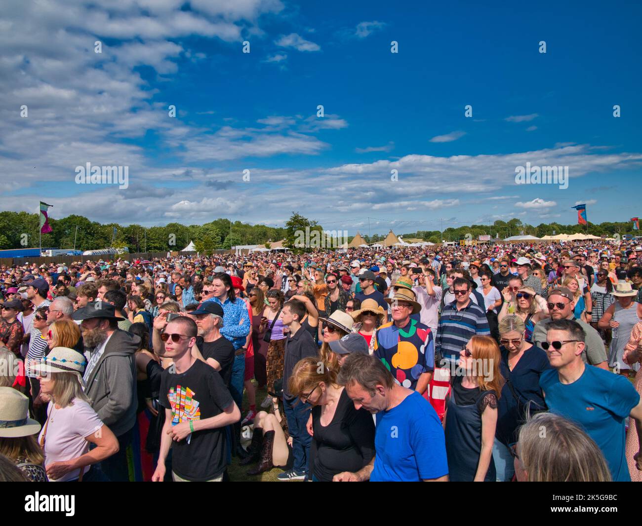 Ein großes Publikum bei einem Sommer-Musikfestival im Freien in England, Großbritannien. Aufgenommen an einem sonnigen Tag mit blauem Himmel. Stockfoto