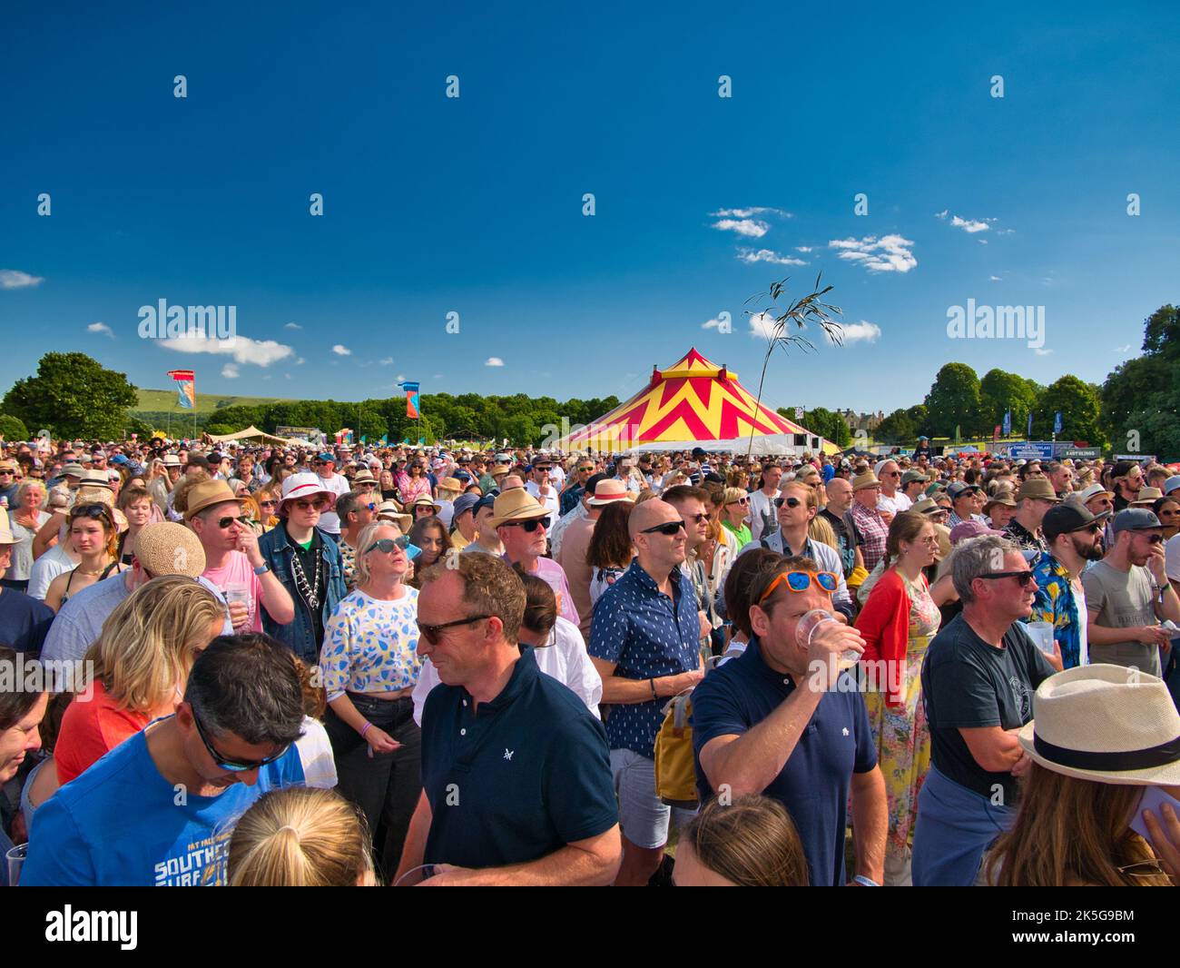 Ein großes Publikum bei einem Sommer-Musikfestival im Freien in England, Großbritannien. Aufgenommen an einem sonnigen Tag mit blauem Himmel. Stockfoto