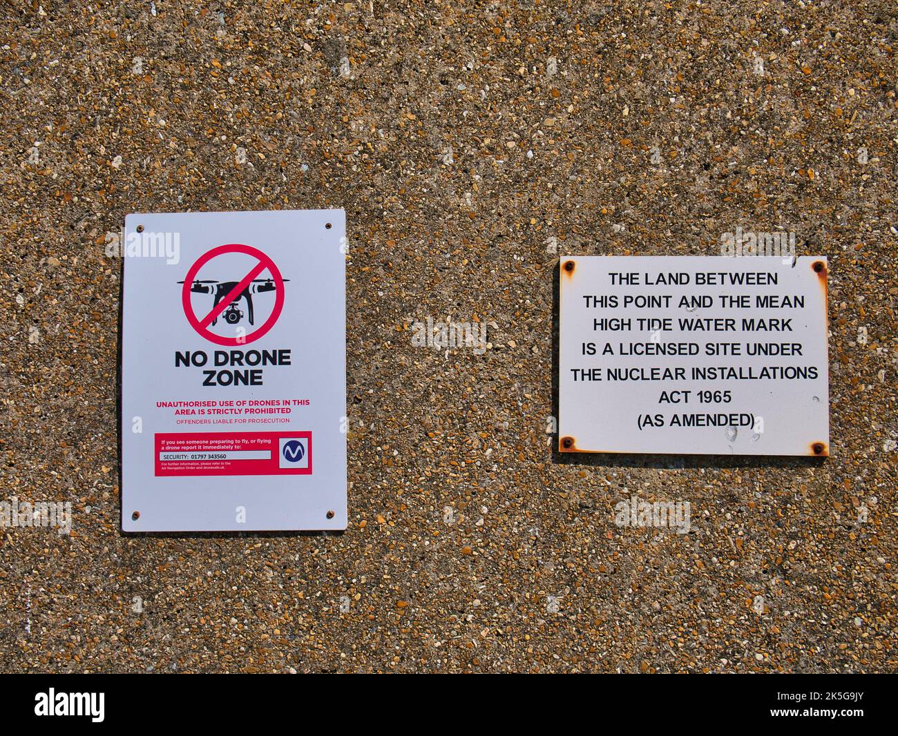 Schilder an der Umfassungsmauer der Kernkraftwerke von Dungeness warnen davor, dass Drohnenflüge verboten sind und das Gebiet kontrolliert wird Stockfoto