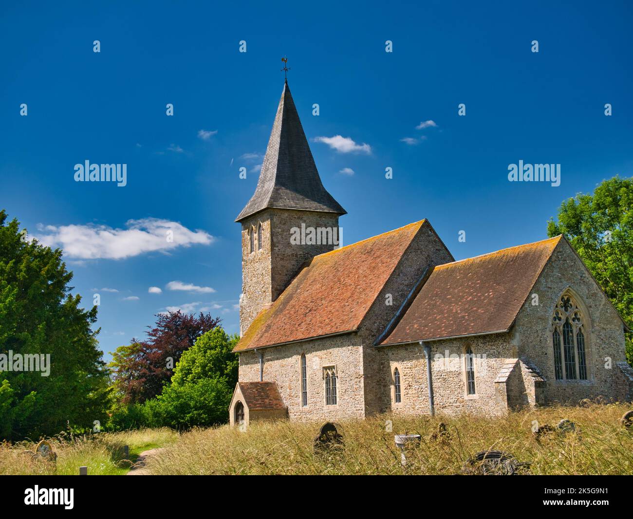Der steinerne Glockenturm und die Gebäude der St. Mary und St. Radegund Kirche im Dorf Postling, Kent, Großbritannien. Die Kirche ist normannischen Ursprungs. Stockfoto