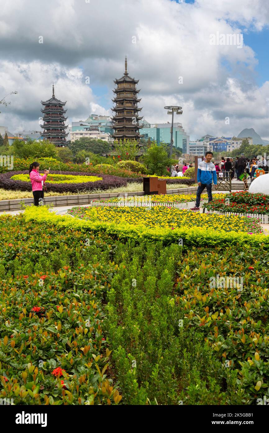 Guilin, China.  Besucher im Garten Shan (Fir) See entlang zu fotografieren.  Sonne und Mond Pagoden im Hintergrund. Stockfoto