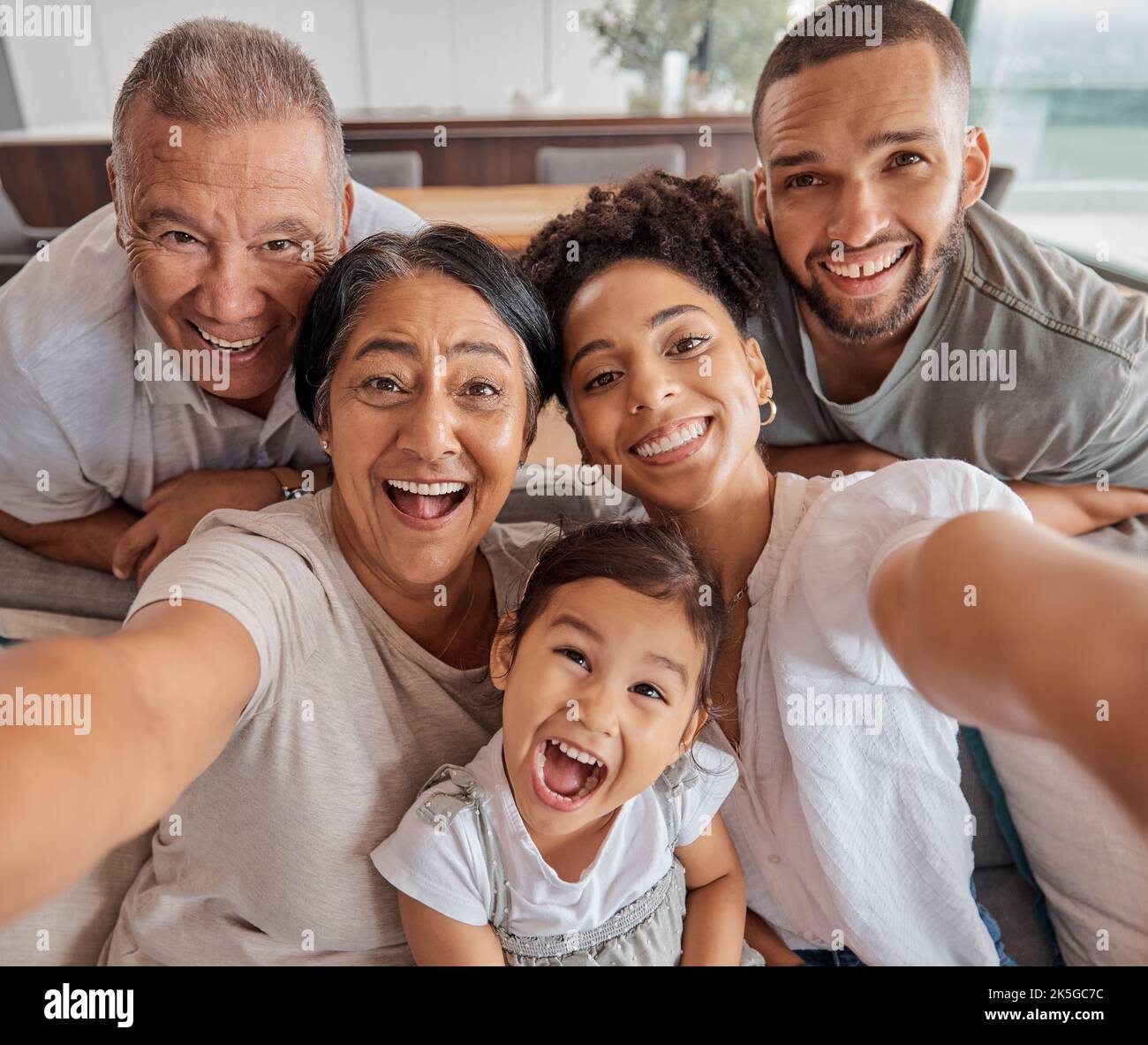 Verrücktes Selfie, Porträtfamilie und Großeltern, die vor Liebe zu Kindern auf dem Sofa im Wohnzimmer lustig sind. Mädchen, Mutter, Vater und Senioren Stockfoto