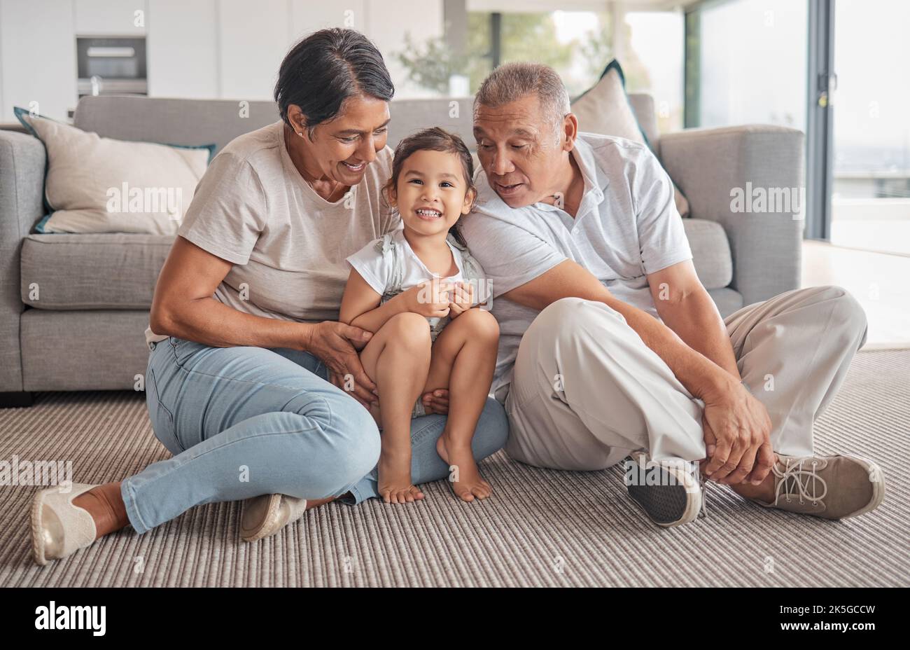 Großeltern, kleine Mädchen und lieben es, sich im Wohnzimmer zu Hause zu entspannen. Portrait von glücklichen Kind lächelt in liebevoller, Spaß Stockfoto