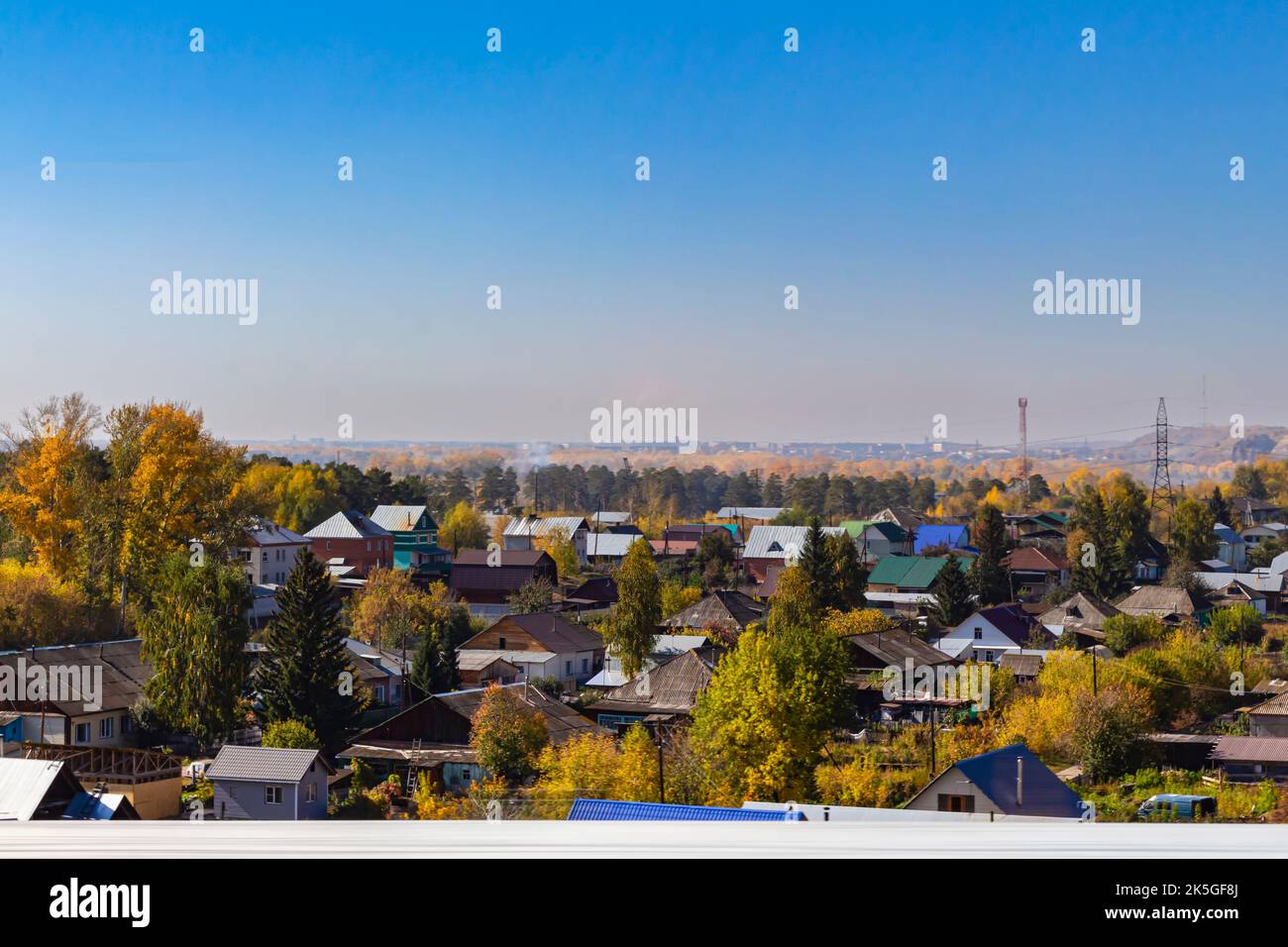 Luftaufnahme der traditionellen Holzhäuser, die den Zustand der Bevölkerung in der Nähe des Flusses Biya auf dem Hintergrund der Herbstlandschaft mit blauem Himmel zeigen. Chaotischer Betrug Stockfoto
