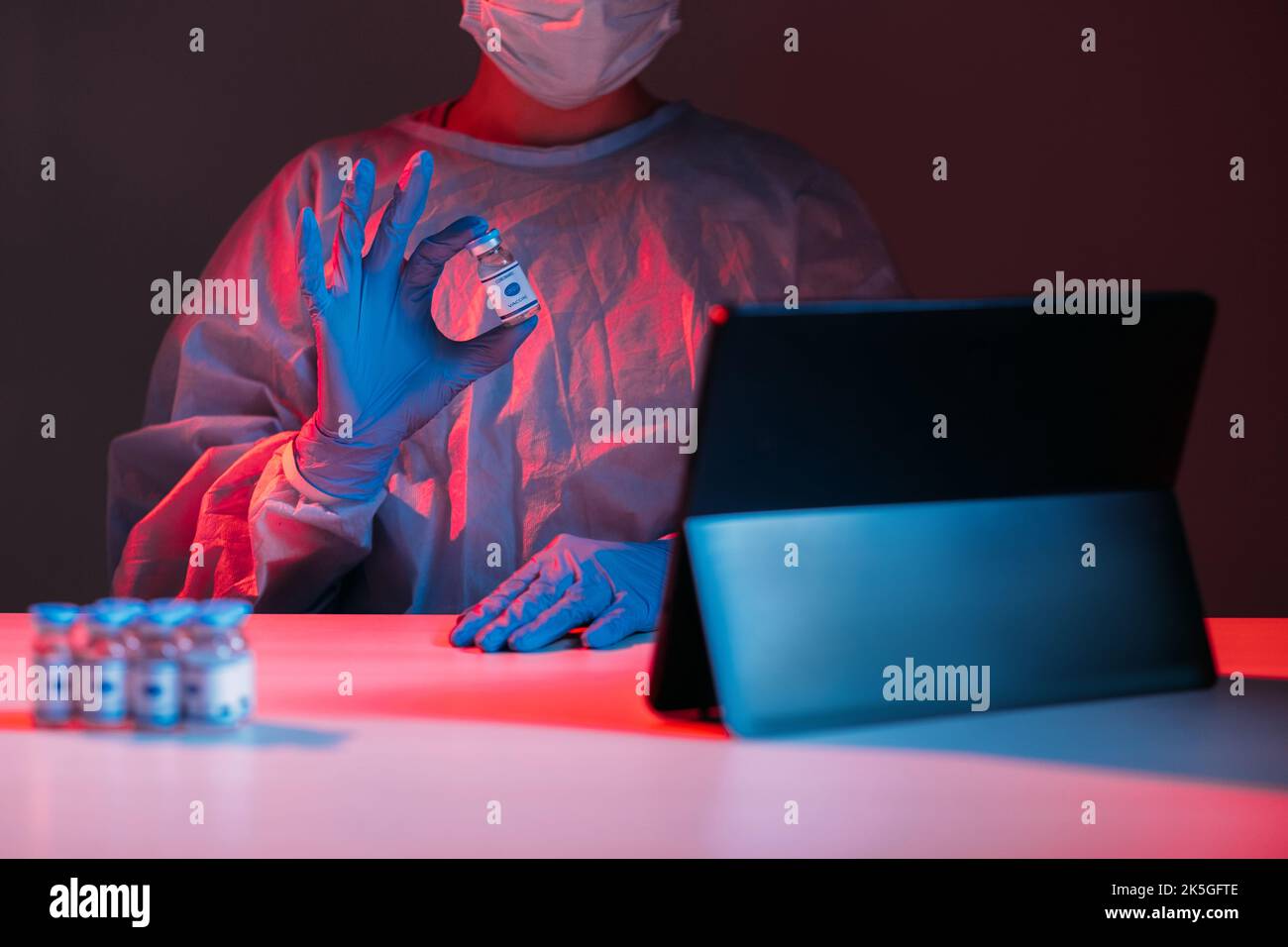 Impfstoffzulassung. Covid-19-TeleheHealth. Virtuelle Versorgung. Medizinische Beratung online. Ärztin in PSA-Handschuhen, die die Dosis der Ampulle auf der Tablette online in rot-blau zeigen Stockfoto