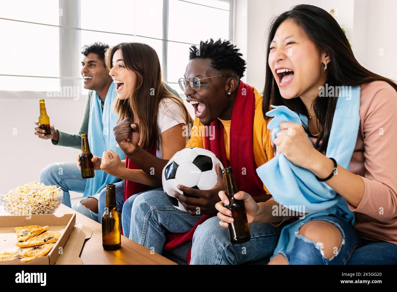 Multiethnische junge Fußballfans unterstützen ihre Nationalmannschaft im Fernsehen Stockfoto
