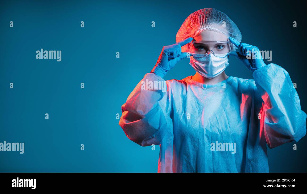 Covid-19-Schutz. Pandemiehygiene. Quarantänesicherheit durch Coronavirus. Porträt einer selbstbewussten Ärztin mit Schutzbrille ppe Gesichtsmaske Handschuhe in rot Stockfoto