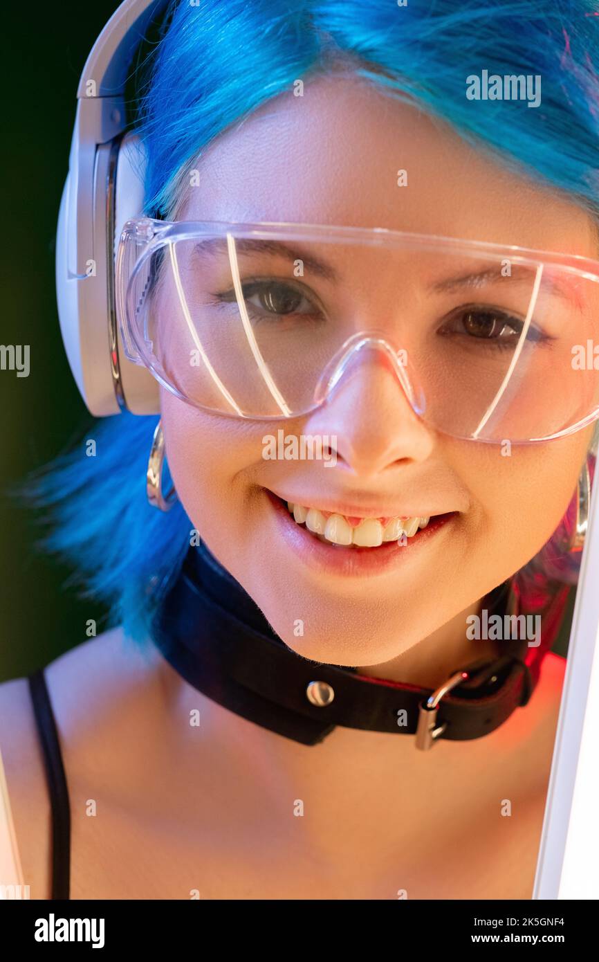Cyberpunk-Gesicht. Generation z. Techno Mode. Porträt von schönen futuristisch lächelnden jungen Modell Frau in LED Neon-Licht Hintergrund. Stockfoto