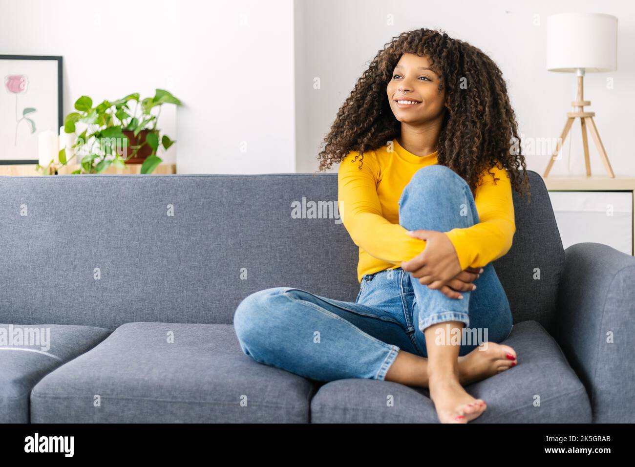 Entspannte junge afroamerikanische Frau, die zu Hause auf dem Sofa sitzt Stockfoto